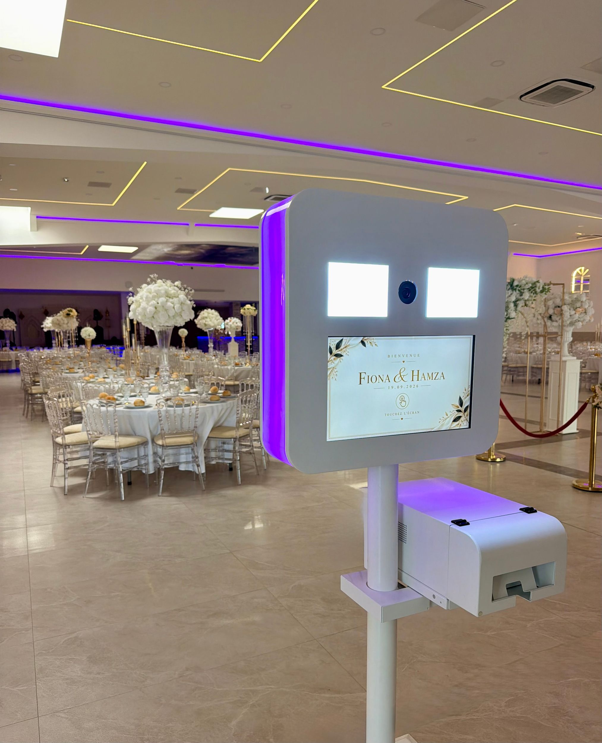 Photobooth installé dans une salle de réception avec écran personnalisé.