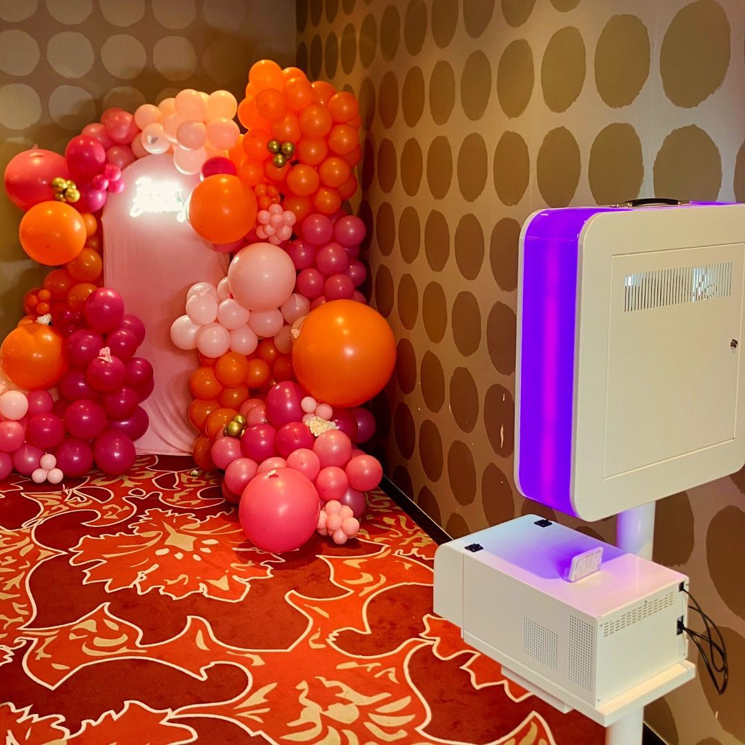 Photobooth avec imprimante installé devant un décor de ballons.
